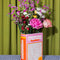 pink word search puzzle book shaped ceramic vase with a bouquet of colorful flowers inside