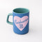 blue ceramic mug with light pink heart and cursive' bookworm' across the front with teal handle and interior