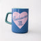 blue ceramic mug with light pink heart and cursive' bookworm' across the front with teal handle and interior