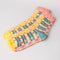 side view of coral, teal, cream and yellow plaid chenille socks with coral ruffle top and cream grip bottoms