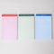 set of three ini legal pads: red/pink with 'these are some serious notes' on the top, green with 'don't forget! write it down!' and blue with 'i did my best' laid flat on a table