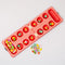 top view of red and cream gingham mancala board with colorful fruit game pieces