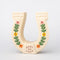 front view of cream horseshoe ceramic vase with colorful flower trim and 'best of luck' stamp in the center
