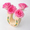 top view of cream horseshoe ceramic vase with colorful flower trim and 'best of luck' stamp in the center with pink roses inside