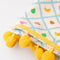 up close of white tea towel with all fruit print and yellow pom trim