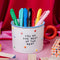 white mug that says 'you make every moment fun' with red round handle, colorful 3D dots and blue trim filled with pens