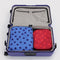 set of 2 large packing cubes with red and bright red dots and blue with navy polka dots in a suitcase