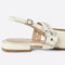 side view of cream slingback flat with large grommet buckle and square toe