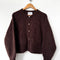 dark brown oversized cardigan with shell buttons and two front patch pockets on a hanger
