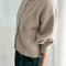 sideview of model wearing cream/tan oversized cardigan with shell buttons and two front patch pockets