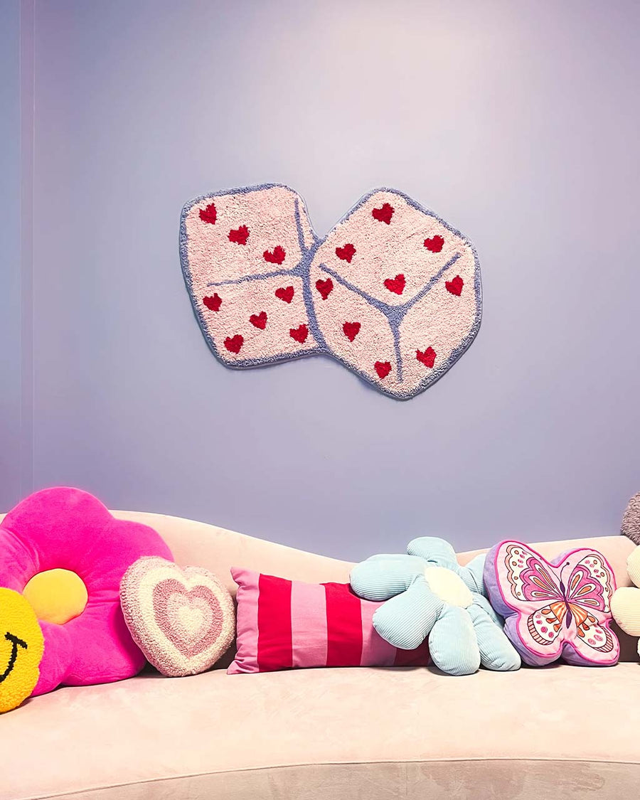 pink heart dice rug with purple border hanging on wall