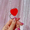 up close of model holding red heart lolli keychain