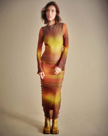 model wearing yellow, brown, orange sunset stripe maxi dress with ruffle seams and long sleeves