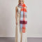 model wearing thick scarf with various shades of blue and red checkers and fringe