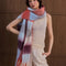 model wearing thick scarf with various shades of blue and red checkers and fringe