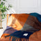 navy, light blue, orange and yellow checkered throw blanket with fringe on a couch