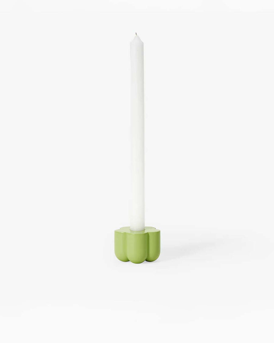 green flower shaped holder with a taper candle in it