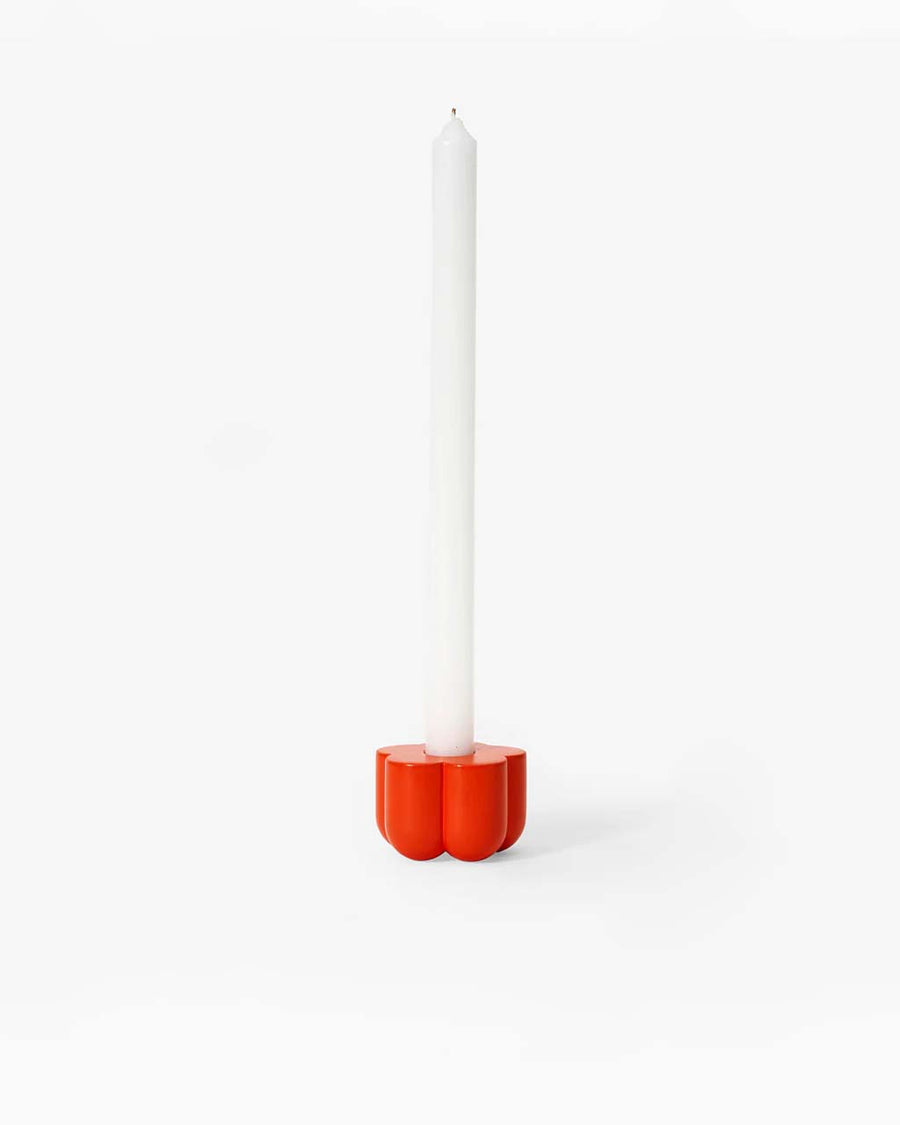 red flower shaped holder with a taper candle in it