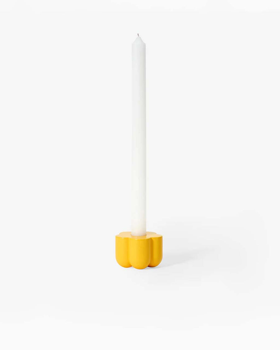 yellow flower shaped holder with a taper candle in it