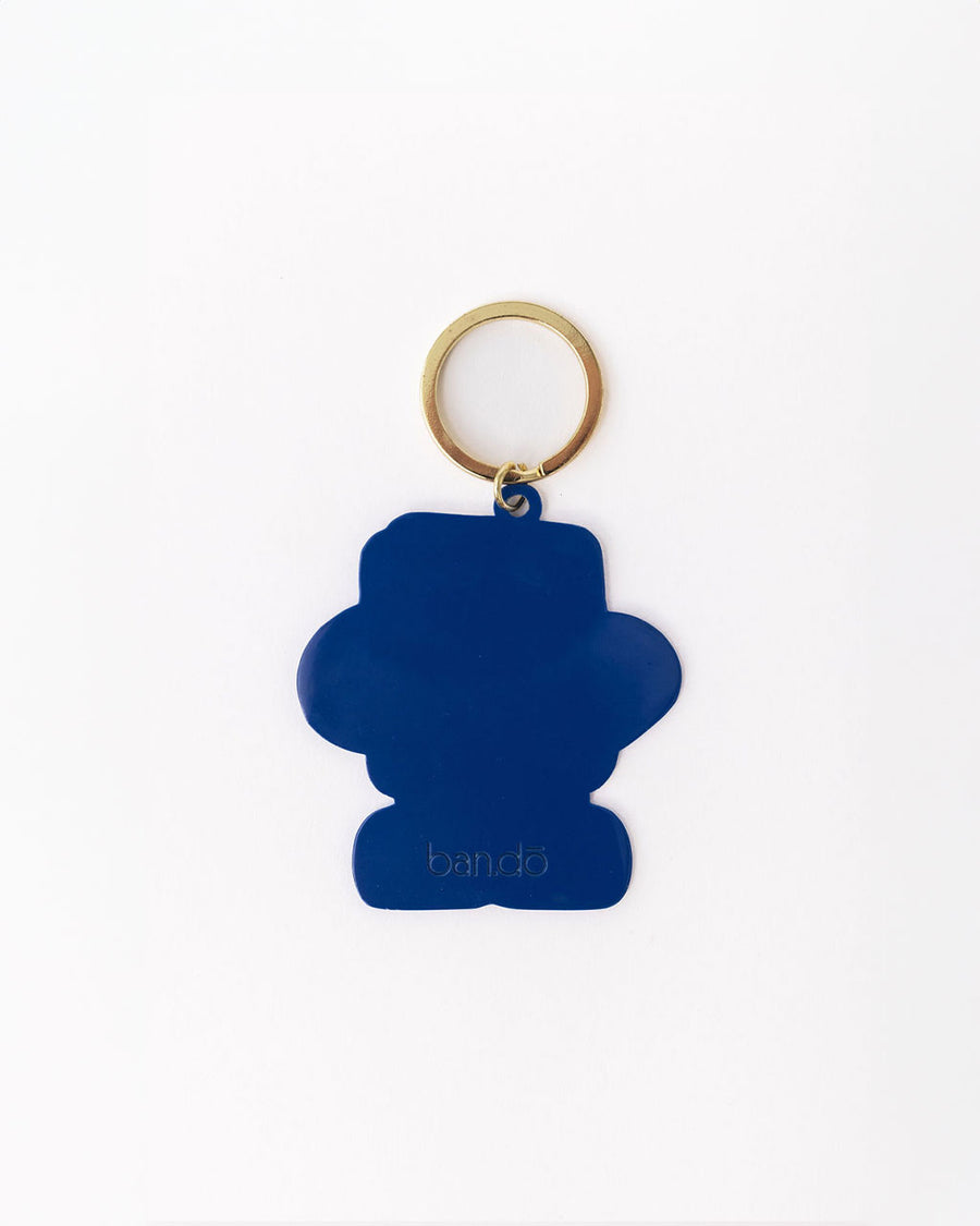 back view of enamel keychain with green book man with arms, face and legs