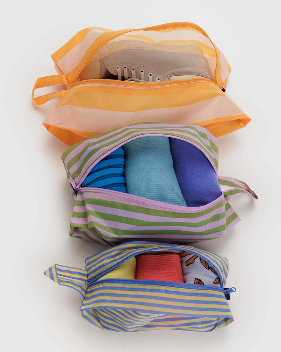 set of 3 zip pouches: small blue and yellow stripe, meduium pink and green stripe and large orange and white stripe with items inside