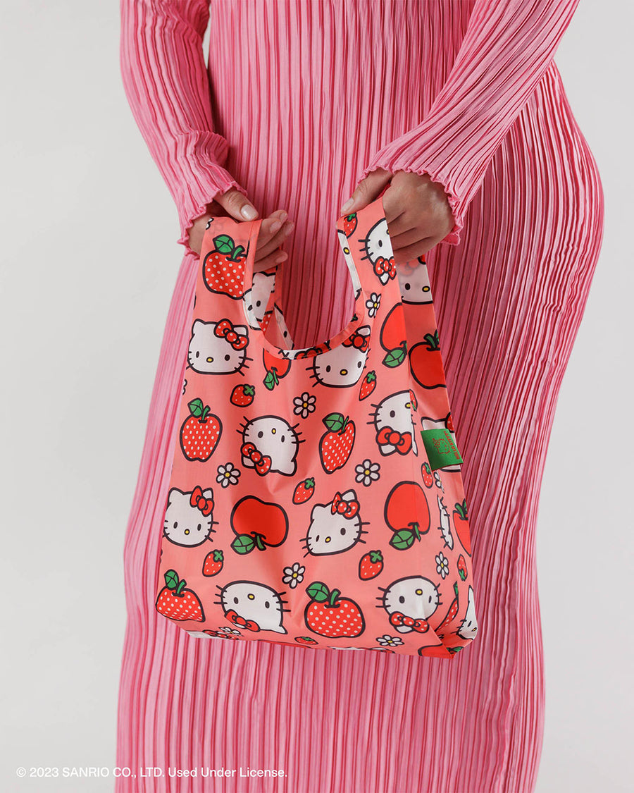 model holding pink baby baggu with apple and hello kitty face print