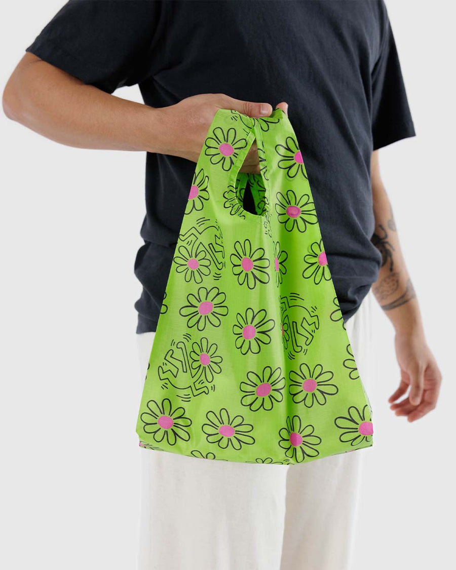 model carrying lime green keith haring baby baggu with with floral print