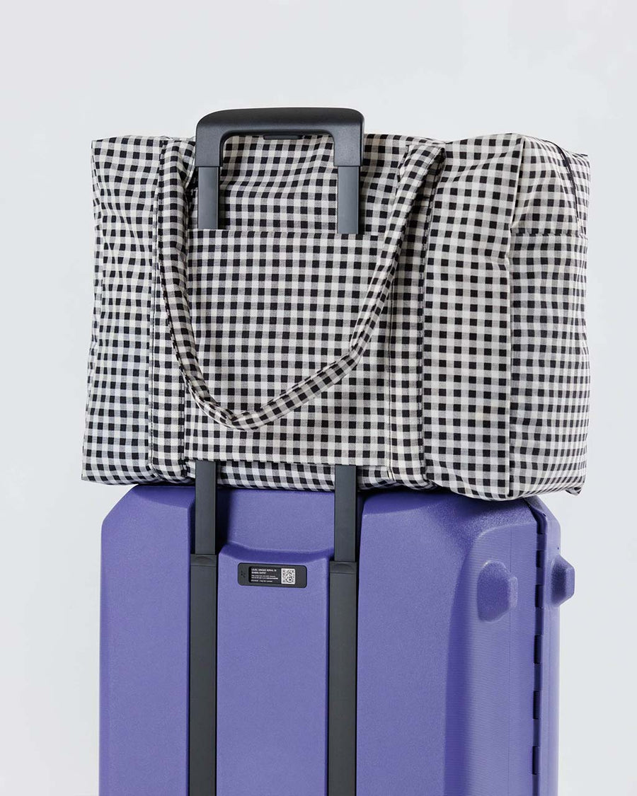 white and black gingham baggu cloud carry-on bag on suitcase