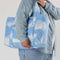 model carrying blue cloud carry on bag with realistic cloud print