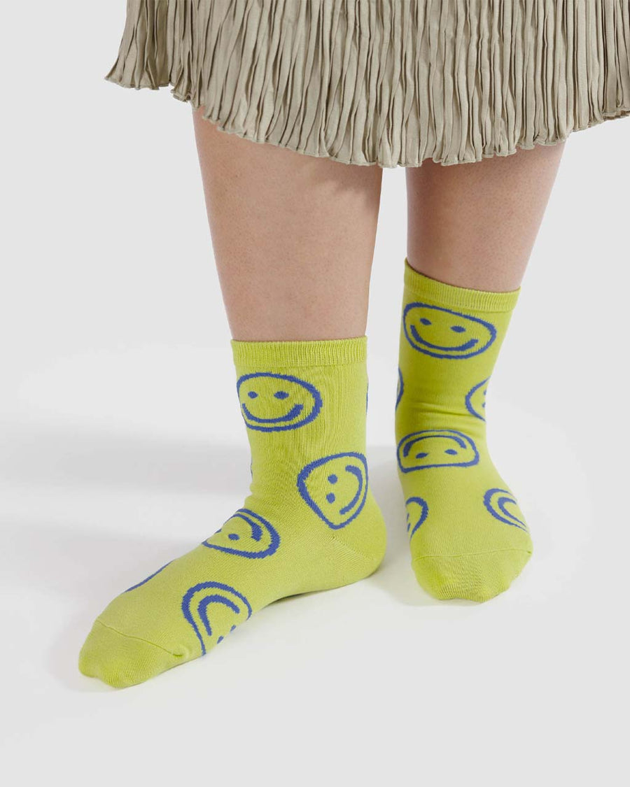 model wearing neon yellow crew socks with periwinkle smiley face print