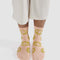 model wearing light pink crew socks with yellow/green smiley face print