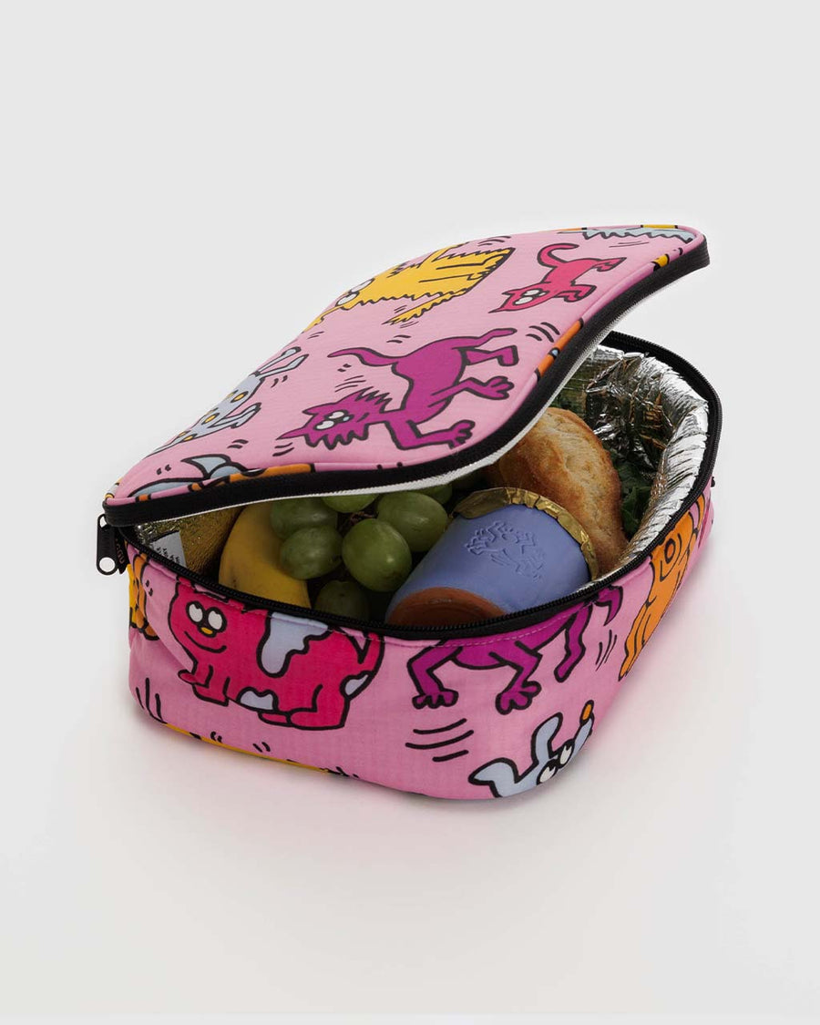 interior of pink keith haring lunch box with colorful dog and cat print with food inside