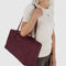 model slinging mahogany rectangular bowler bag with bag charm clip over their shoulder