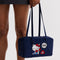 model holding navy nylon bowler bag with embroidered hello kitty talking on a red phone