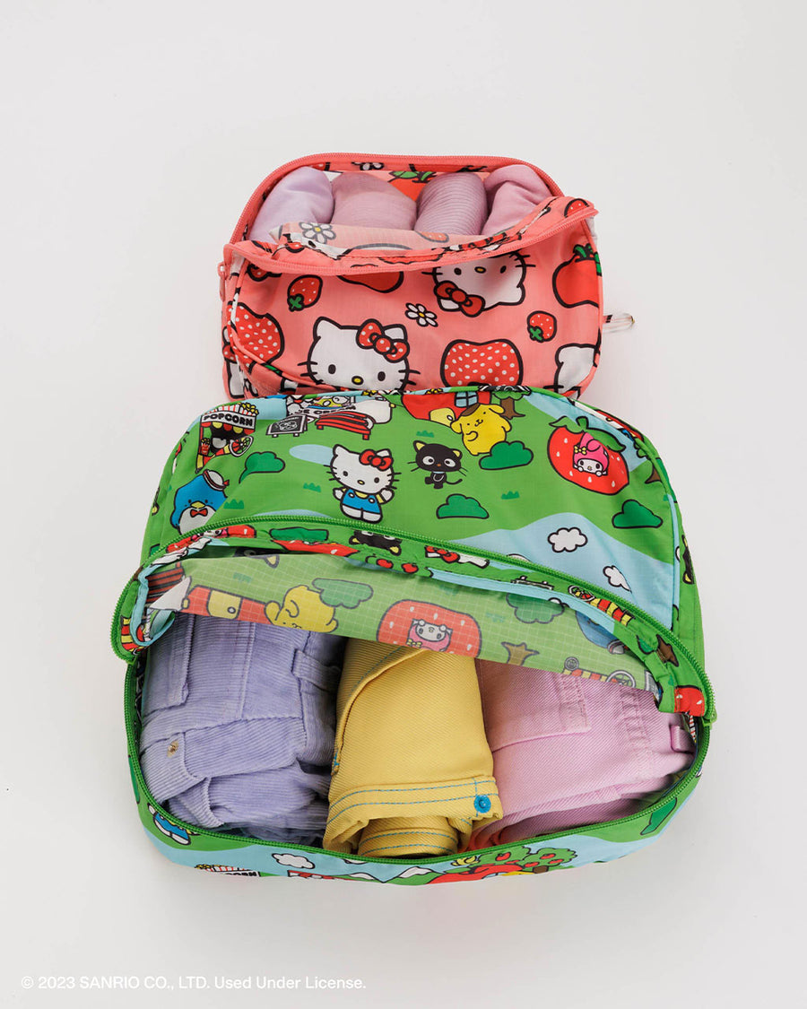 set of two packing cubes: small pink hello kitty apple and medium green hello kitty and friends scene with clothing inside