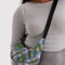 model carrying pink, green and blue plaid small crescent bag with black adjustable strap