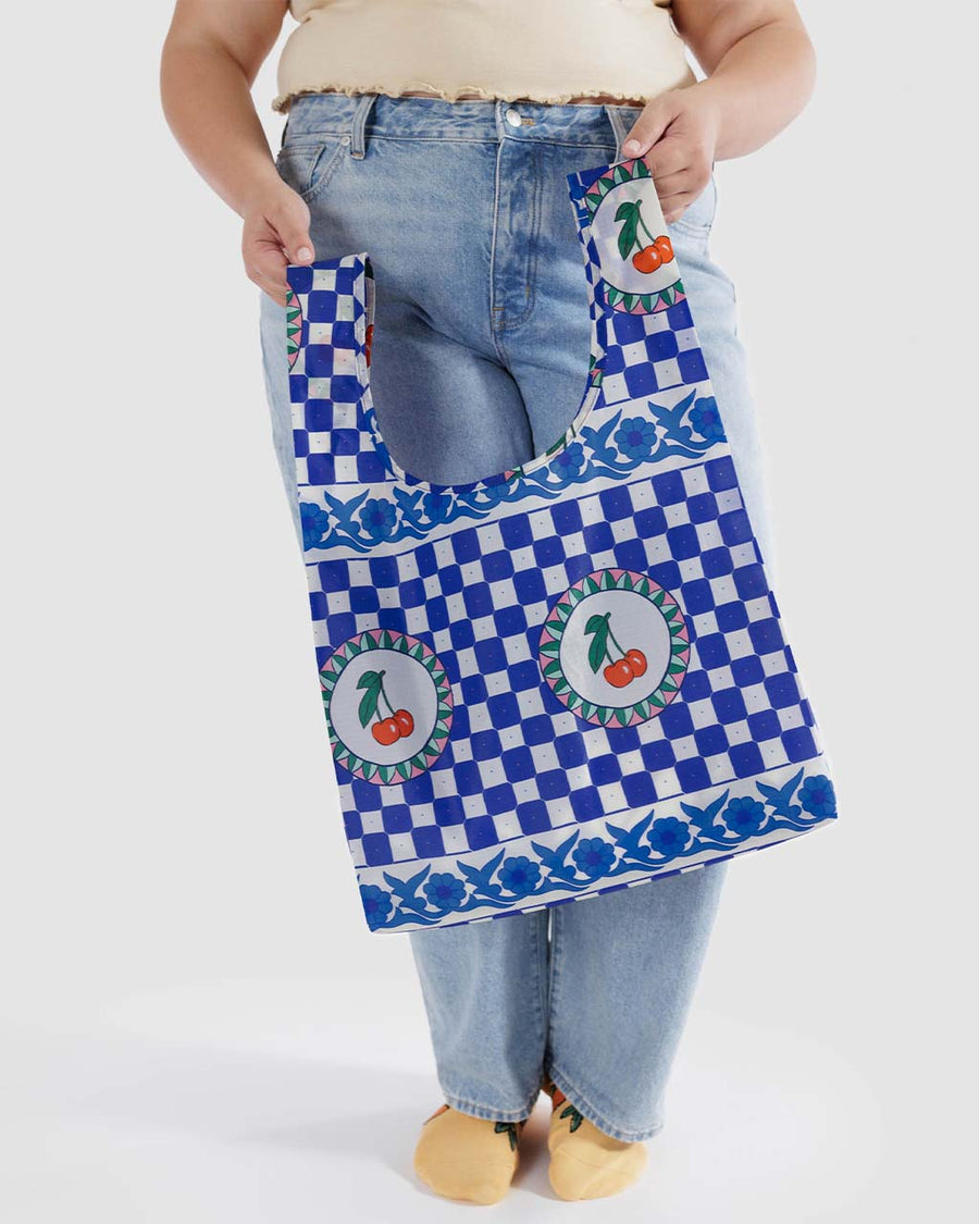 model holding blue standard baggu bag with checkered tile print with cherry design
