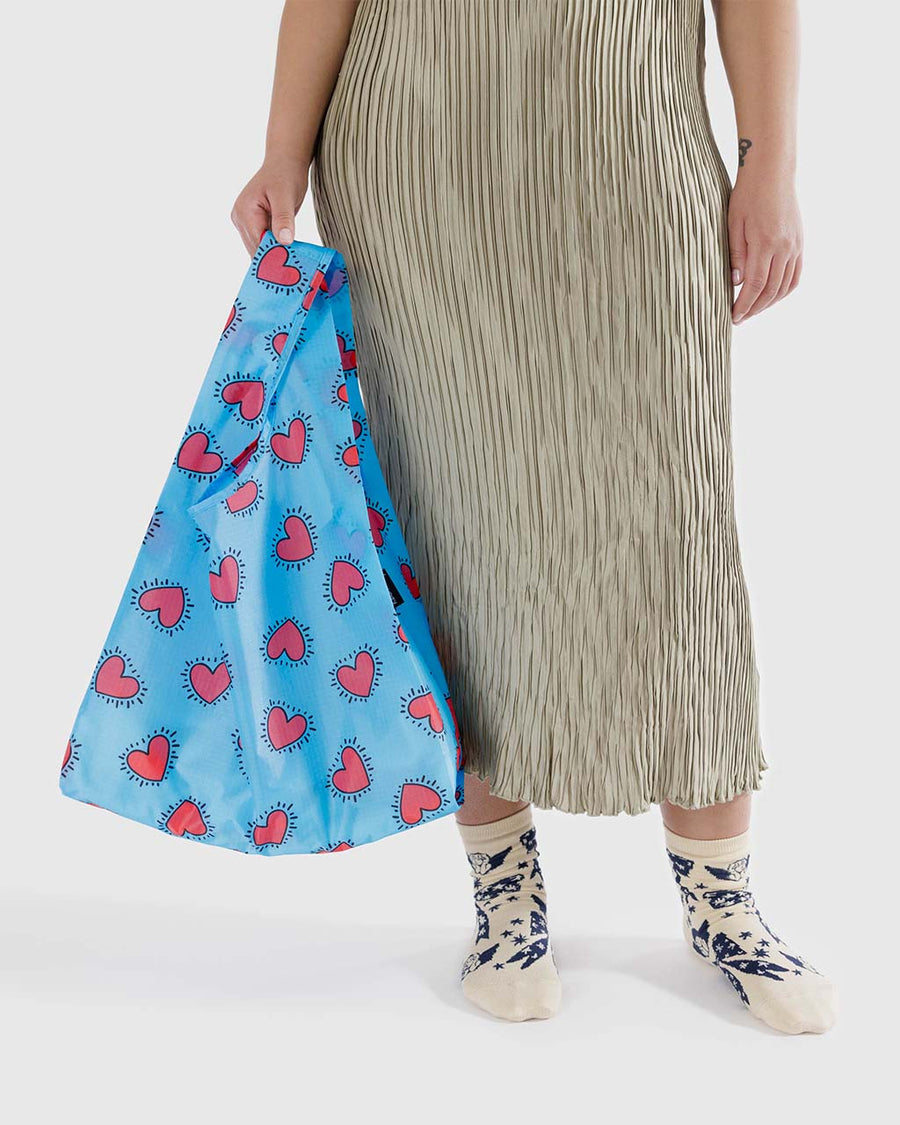 model holding blue keith haring standard baggu with red heart print