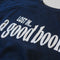up close of navy sweatshirt with white 'LOST IN... GOOD BOOK' across the front