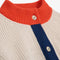 up close of cream knit cardigan with yellow sleeve cuffs, coral trim and navy button front with embroidered couple on bust