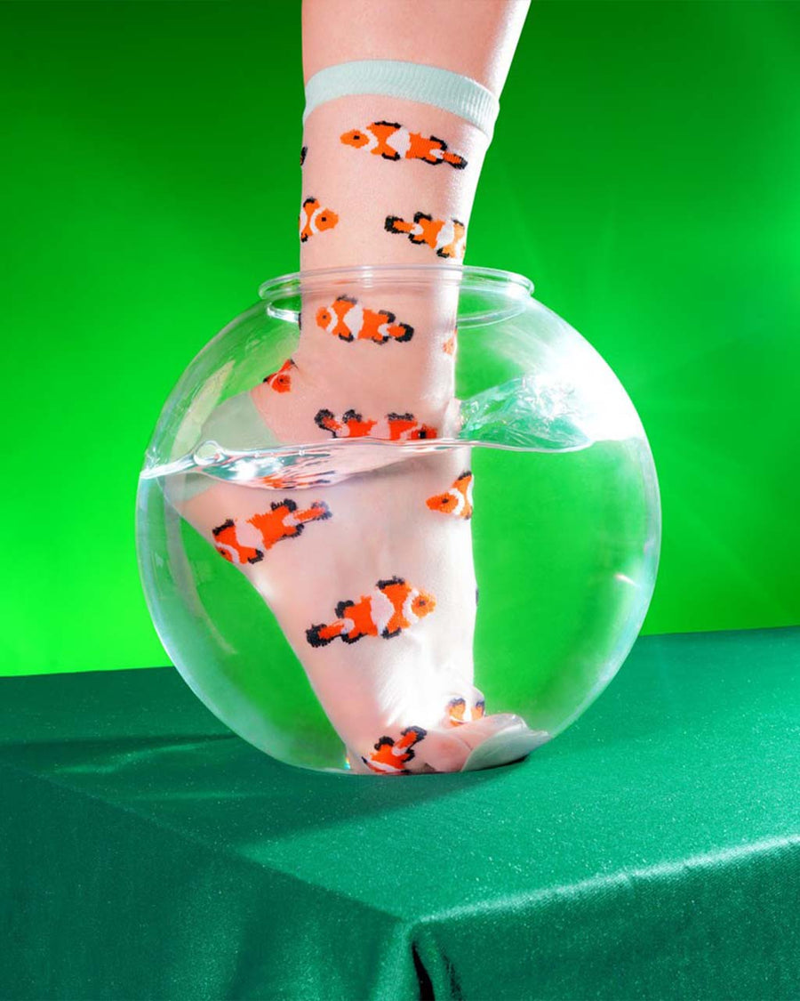 model with foot in fishbowl wearing sheer socks with clownfish print and white trim