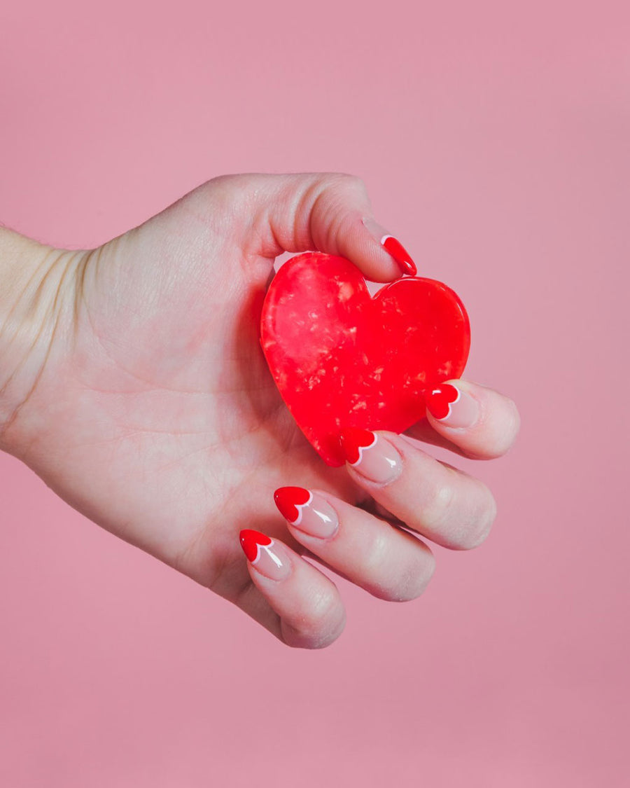 model holding red heart shaped hair claw