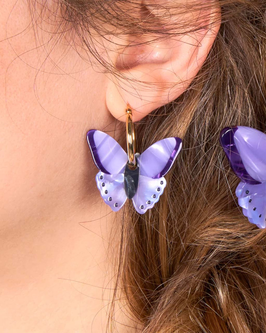 model wearing purple butterfly earrings with gold hoops