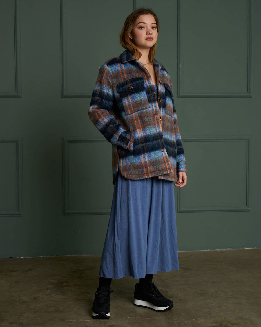 side view of model wearing blue and brown wool plaid jacket