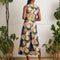 back view of model wearing blue jumpsuit with picnic food print and tie waist