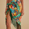 up close of model wearing teal beach sarong with colorful banana and banana leaves print and green fringe