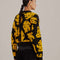 back view of model wearing black cropped cardigan sweater with yellow abstract banana print