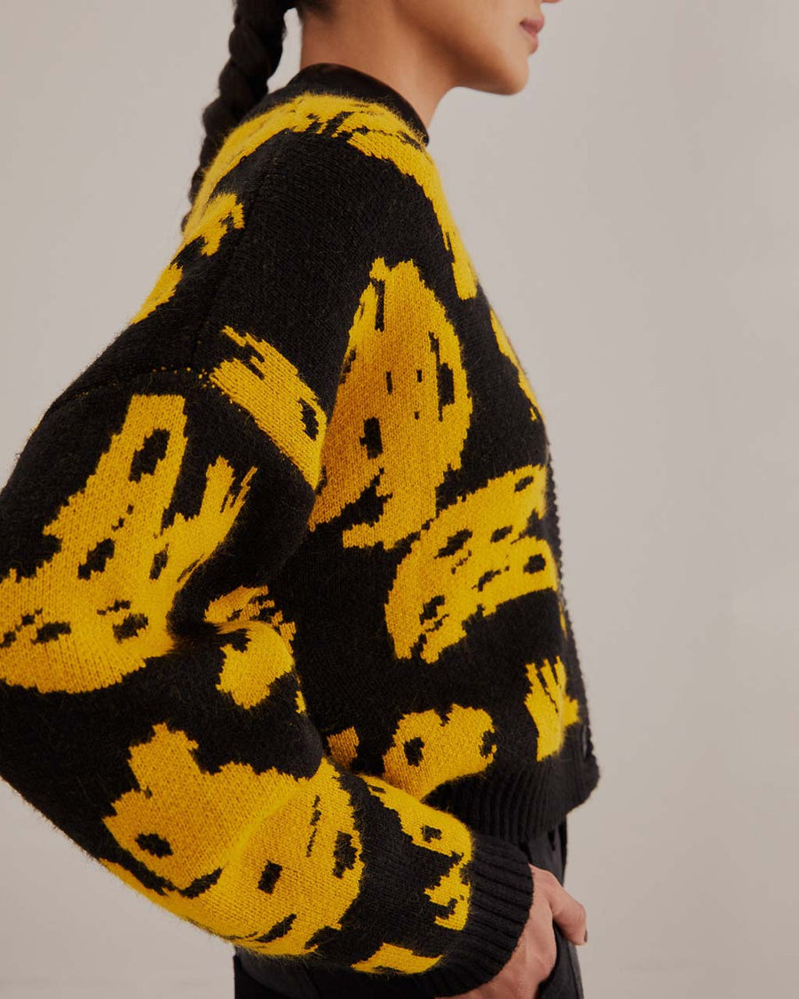 up close of model wearing black cropped cardigan sweater with yellow abstract banana print