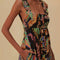up close of model wearing black maxi sundress with button front, low tie back and vibrant foliage print