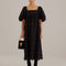 model wearing black eyelet maxi dress with empire waist, puff sleeves and scalloped hem